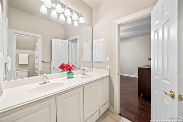 full bath featuring a sink, baseboards, toilet, and double vanity
