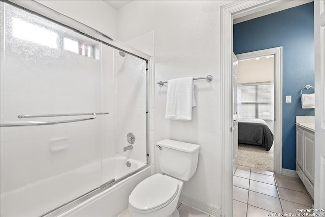 ensuite bathroom featuring tile patterned flooring, vanity, baseboards, combined bath / shower with glass door, and toilet