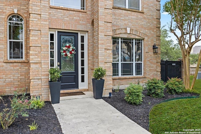 doorway to property with fence and brick siding