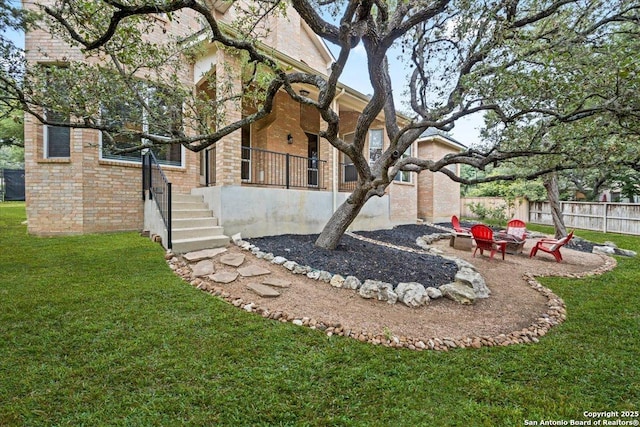 exterior space with a lawn, brick siding, fence, and an outdoor fire pit