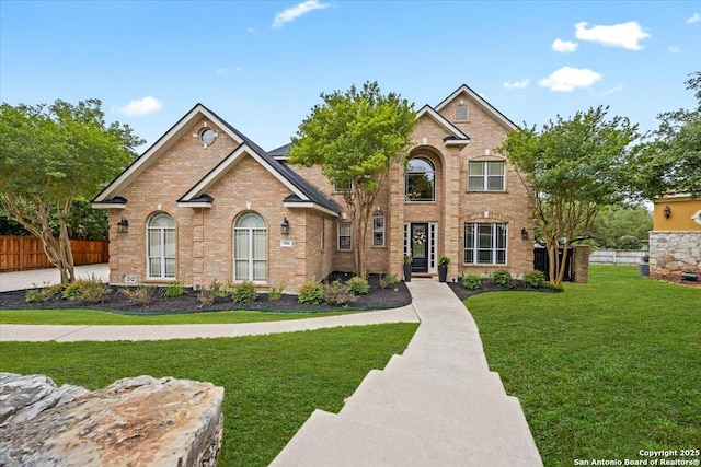 view of front of property with brick siding, fence, and a front yard