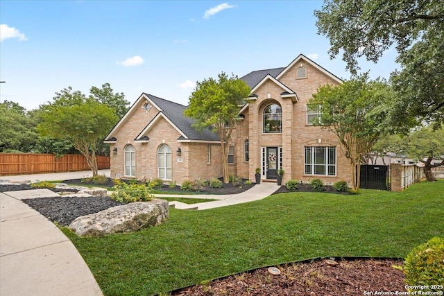 traditional home featuring brick siding, fence, and a front yard