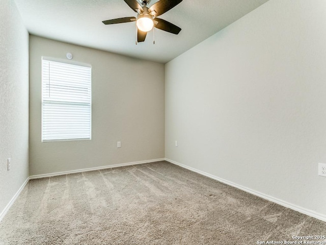 carpeted spare room featuring baseboards and a ceiling fan