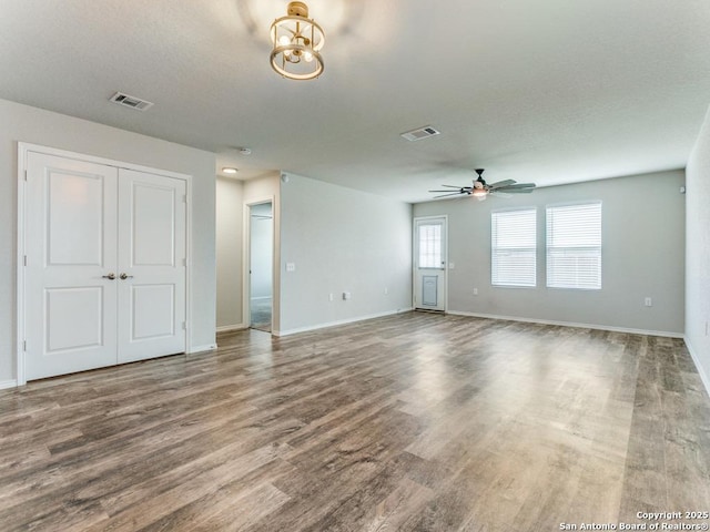unfurnished living room with baseboards, visible vents, and wood finished floors