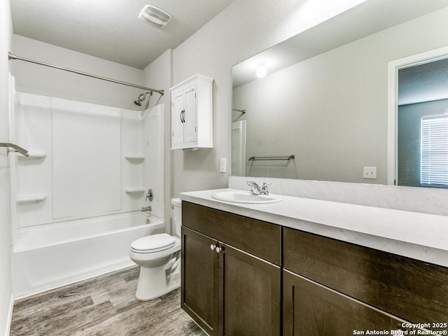 full bathroom featuring vanity, visible vents, wood finished floors, toilet, and  shower combination