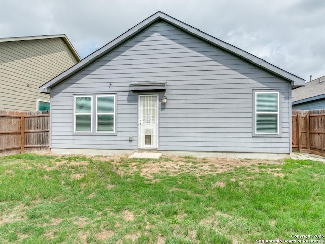 rear view of house featuring a fenced backyard and a lawn