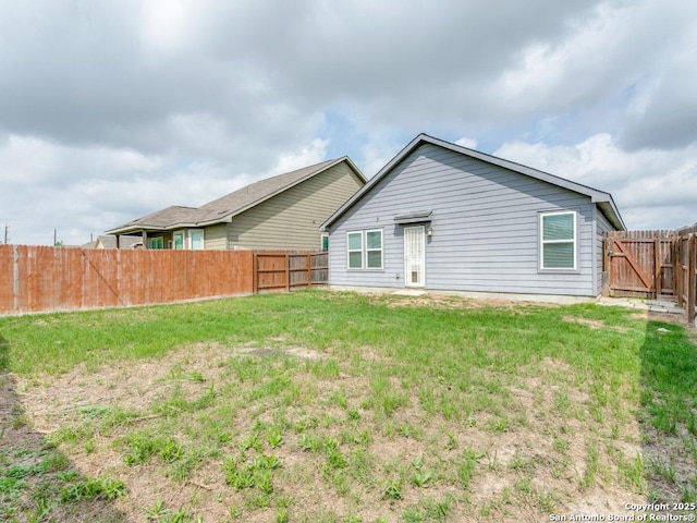 back of house with a fenced backyard and a yard