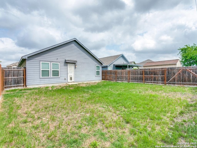 back of house featuring a lawn and a fenced backyard