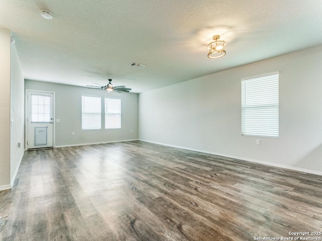 unfurnished living room with visible vents, a ceiling fan, baseboards, and wood finished floors