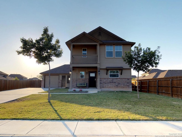 craftsman inspired home with fence, a balcony, a front yard, brick siding, and driveway