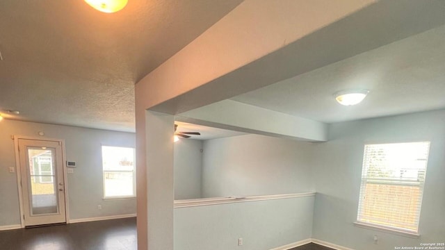interior space with baseboards, a ceiling fan, and dark wood-type flooring