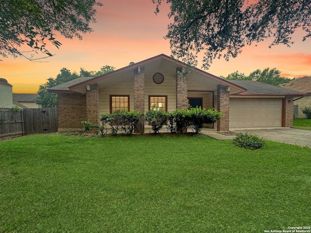 view of front facade with brick siding, a garage, fence, and a yard