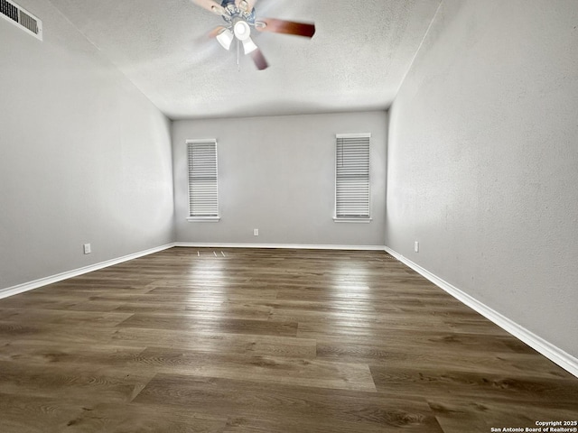 spare room with a textured ceiling, ceiling fan, visible vents, and baseboards