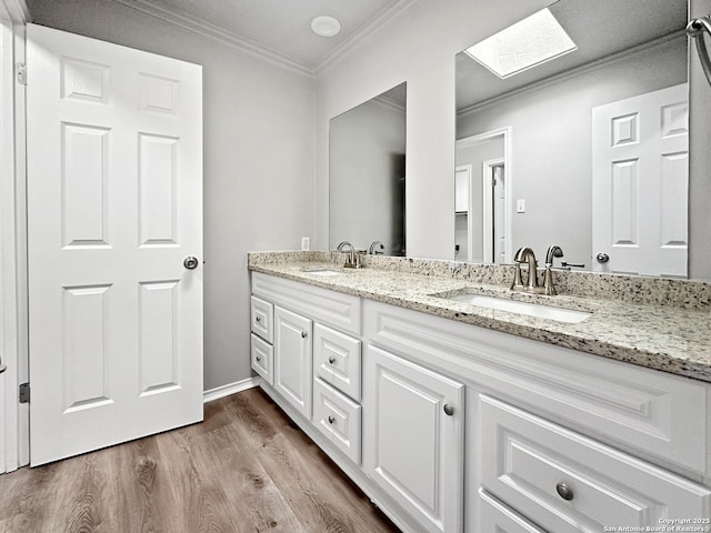bathroom with crown molding, double vanity, a sink, and wood finished floors