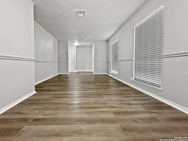 unfurnished room featuring baseboards, wood finished floors, and visible vents