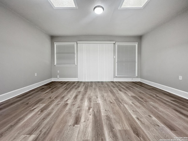 unfurnished bedroom featuring baseboards, wood finished floors, and a skylight