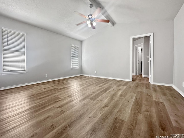interior space featuring baseboards, a ceiling fan, lofted ceiling with beams, and wood finished floors
