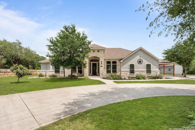 mediterranean / spanish-style house with stucco siding, a front yard, and stone siding