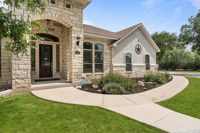 entrance to property featuring a lawn, roof with shingles, and stone siding