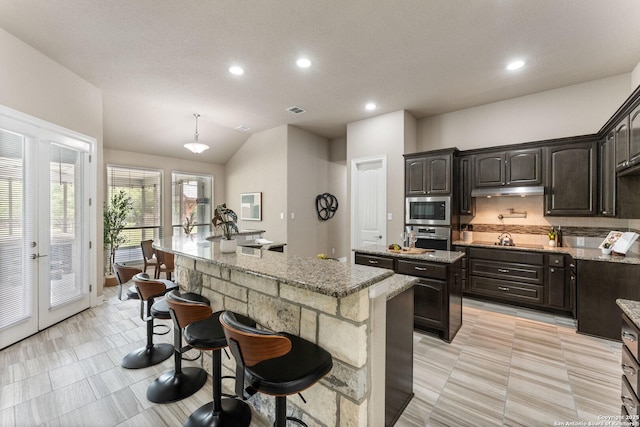 kitchen featuring recessed lighting, appliances with stainless steel finishes, a kitchen bar, and a center island