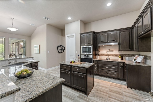 kitchen with visible vents, appliances with stainless steel finishes, tasteful backsplash, a center island with sink, and a sink