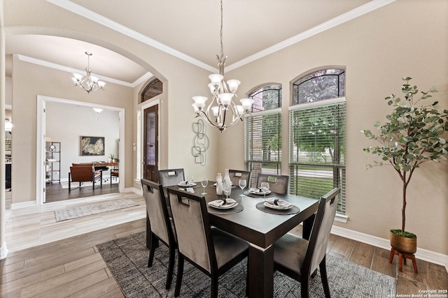 dining space featuring an inviting chandelier, ornamental molding, wood finished floors, baseboards, and arched walkways