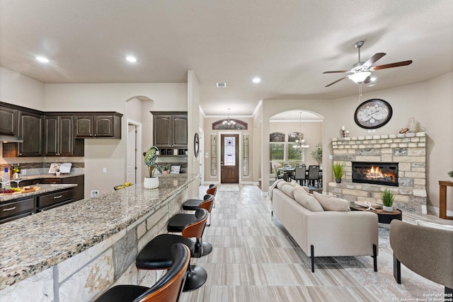 living area featuring recessed lighting, arched walkways, a ceiling fan, and a fireplace