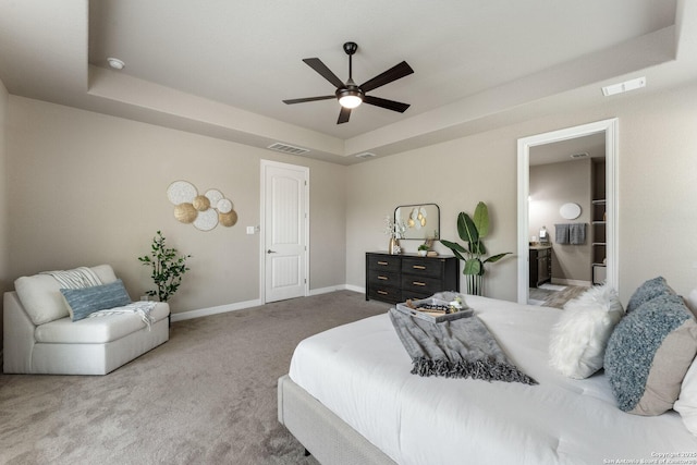 carpeted bedroom with a raised ceiling, baseboards, a ceiling fan, and visible vents
