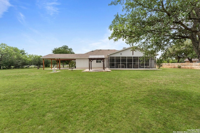 back of property with a sunroom, a lawn, and a patio