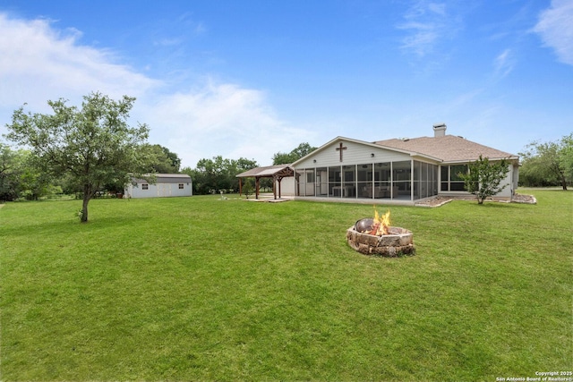 view of yard with a gazebo, a fire pit, and a sunroom