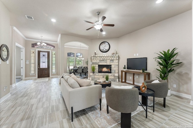 living area with baseboards, ceiling fan with notable chandelier, a stone fireplace, and visible vents