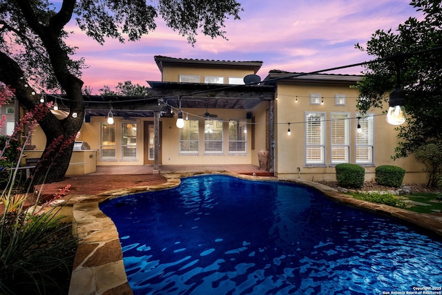 back of house with a ceiling fan, stucco siding, a patio area, and an outdoor pool