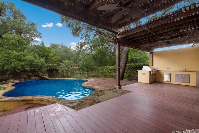 view of swimming pool featuring exterior kitchen, ceiling fan, a wooden deck, and a fenced backyard
