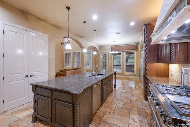 kitchen featuring a sink, stone tile flooring, stainless steel appliances, recessed lighting, and wall chimney exhaust hood