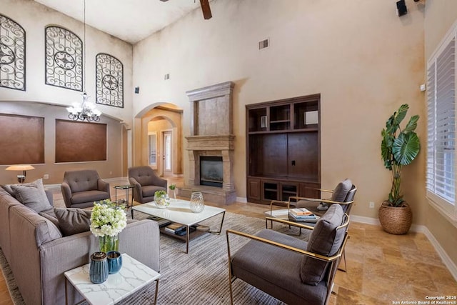 living area with visible vents, a glass covered fireplace, baseboards, a high ceiling, and arched walkways