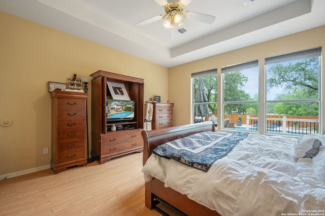 bedroom featuring baseboards, visible vents, a raised ceiling, and light wood-style floors
