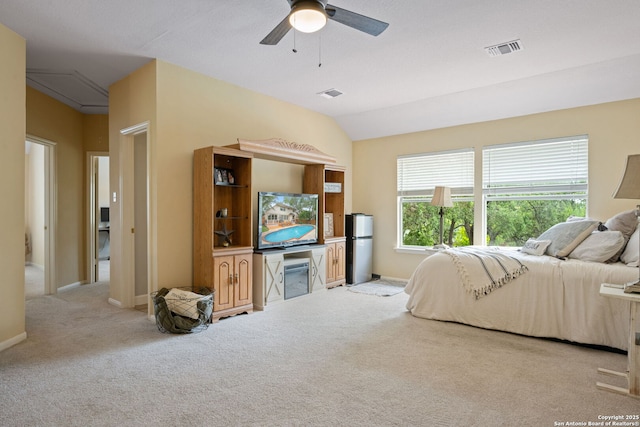 carpeted bedroom with freestanding refrigerator, vaulted ceiling, visible vents, and attic access
