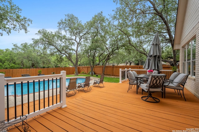 deck with a fenced in pool, outdoor dining space, and a fenced backyard