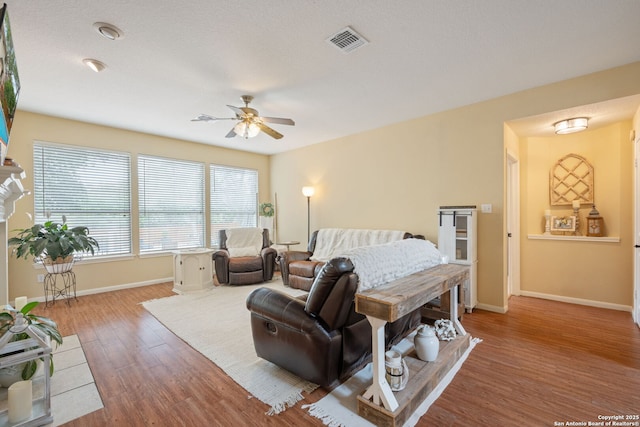bedroom featuring baseboards, a ceiling fan, wood finished floors, and visible vents