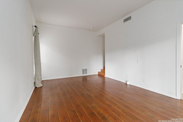 spare room with visible vents, stairs, baseboards, and wood-type flooring