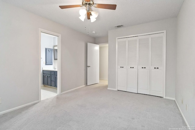 unfurnished bedroom featuring visible vents, baseboards, a closet, light carpet, and ensuite bath