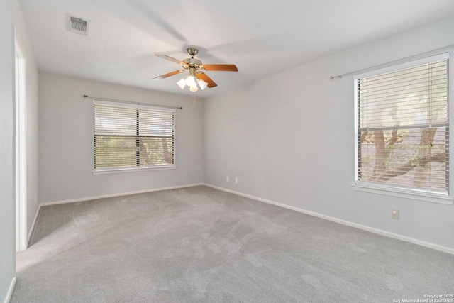 carpeted spare room with baseboards, ceiling fan, and visible vents