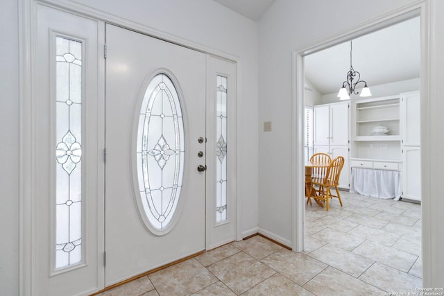 foyer with an inviting chandelier, light tile patterned floors, and baseboards