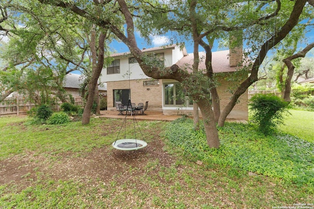 rear view of property featuring a lawn, fence, a chimney, and a patio