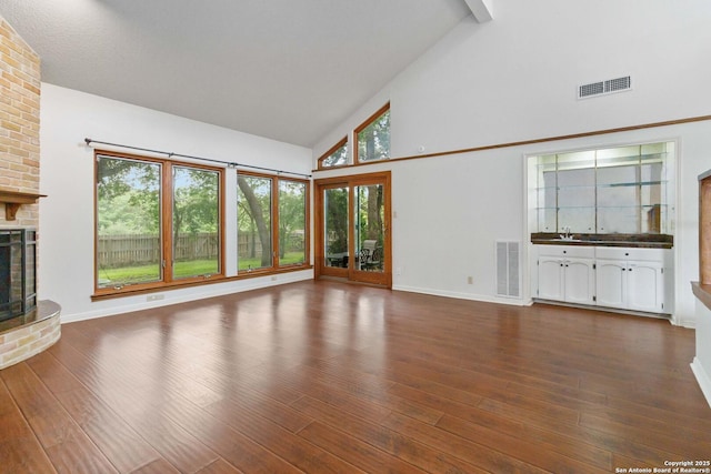unfurnished living room with high vaulted ceiling, visible vents, dark wood finished floors, and a fireplace