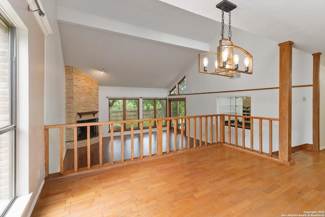 unfurnished room featuring visible vents, a brick fireplace, wood finished floors, beamed ceiling, and a notable chandelier
