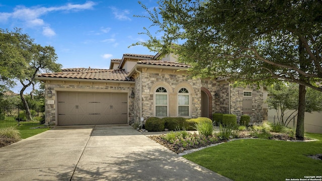 22932 Estacado, San Antonio, TX 78261 - mediterranean / spanish house featuring stone siding, a garage, concrete driveway, and a tile roof