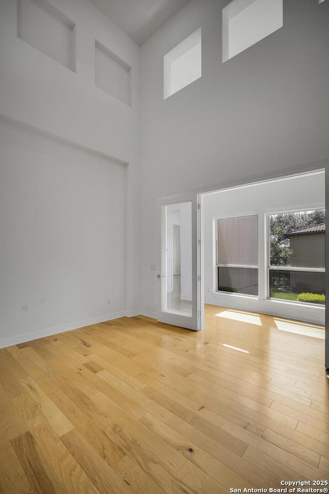 22932 Estacado, San Antonio, TX 78261 - unfurnished living room with a towering ceiling, light wood-style flooring, and baseboards