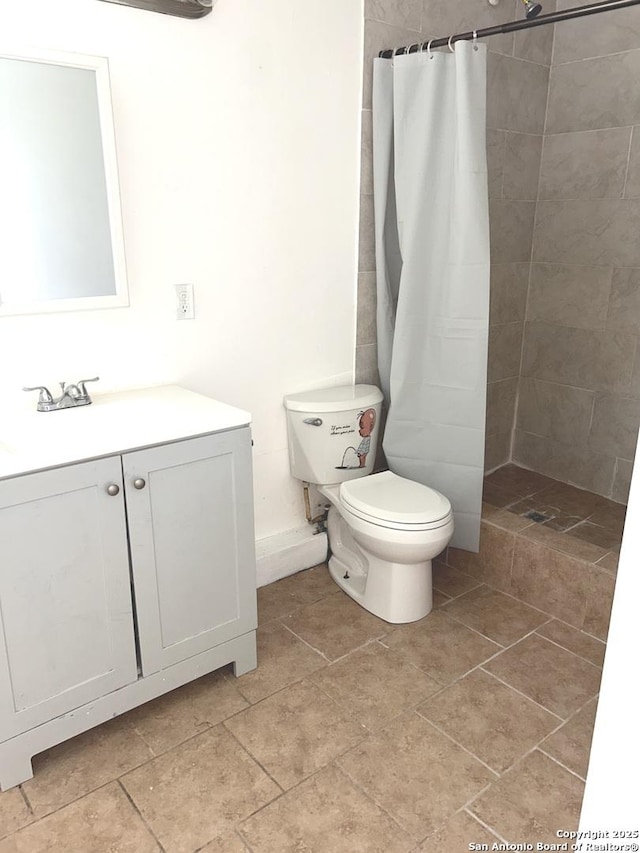 bathroom featuring vanity, a tile shower, and toilet