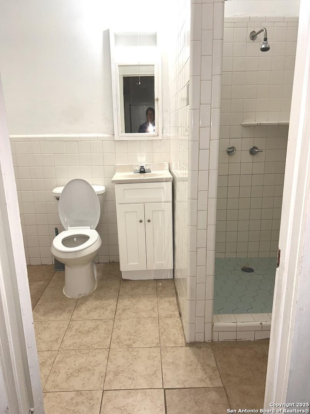 bathroom featuring tile patterned flooring, vanity, toilet, tile walls, and a shower stall